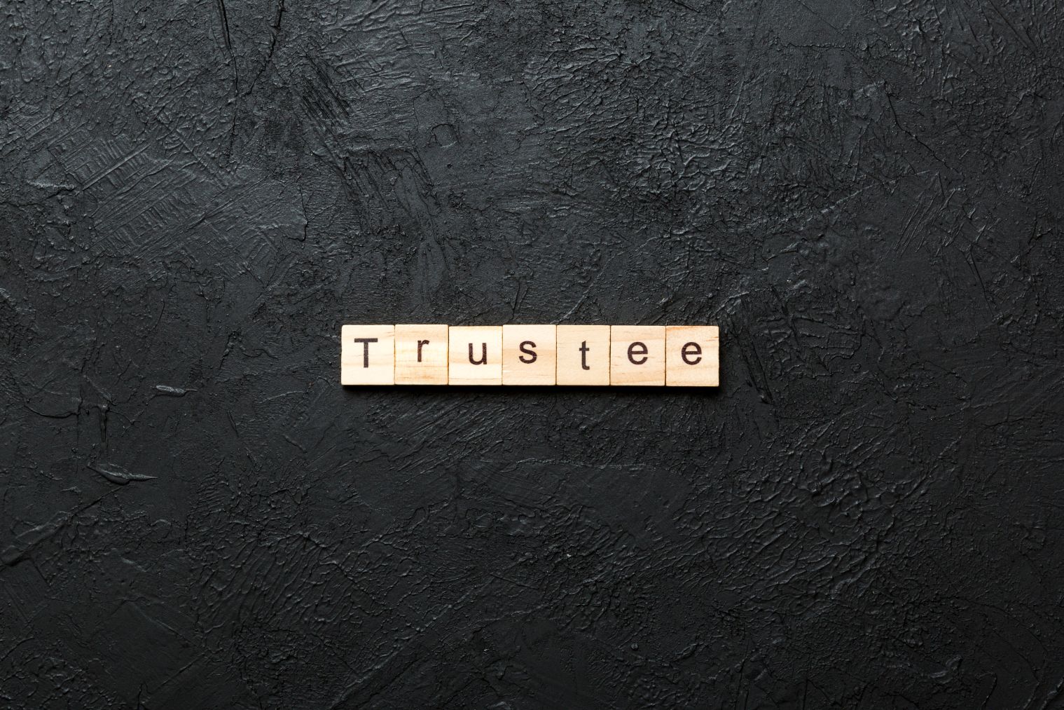 The word trustee spelled out in wooden tiles.